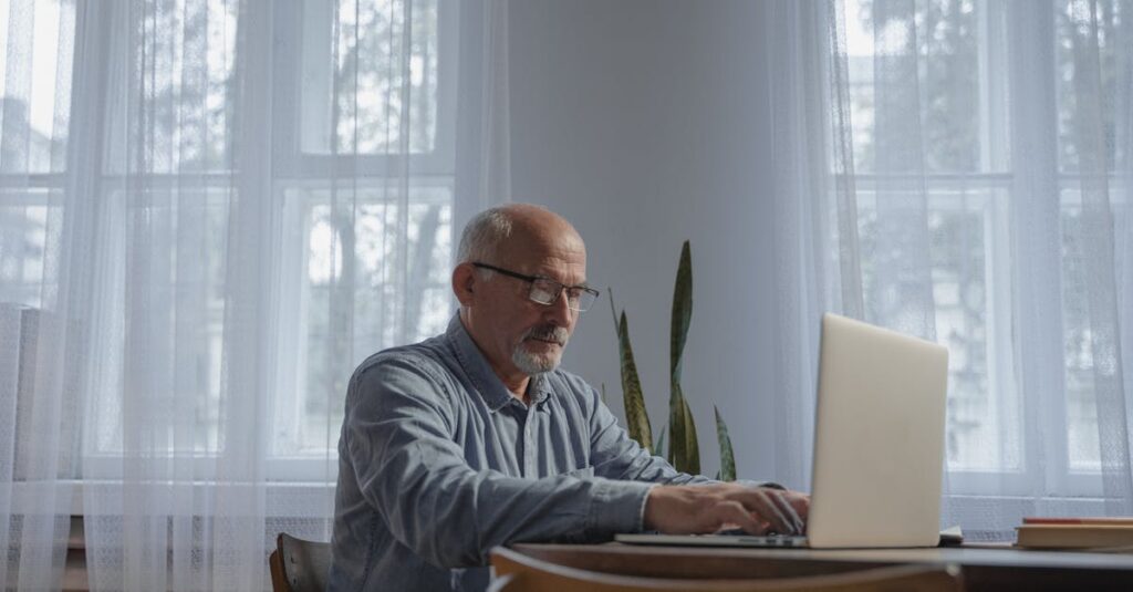 50代・60代のシニアが自宅で落ち着いてノートパソコンを使い、在宅副業に取り組んでいるイメージ